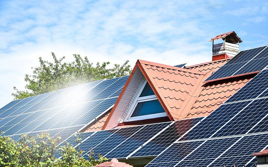 Technician cleaning rooftop solar panels on Oahu with a soft-brush water-fed pole